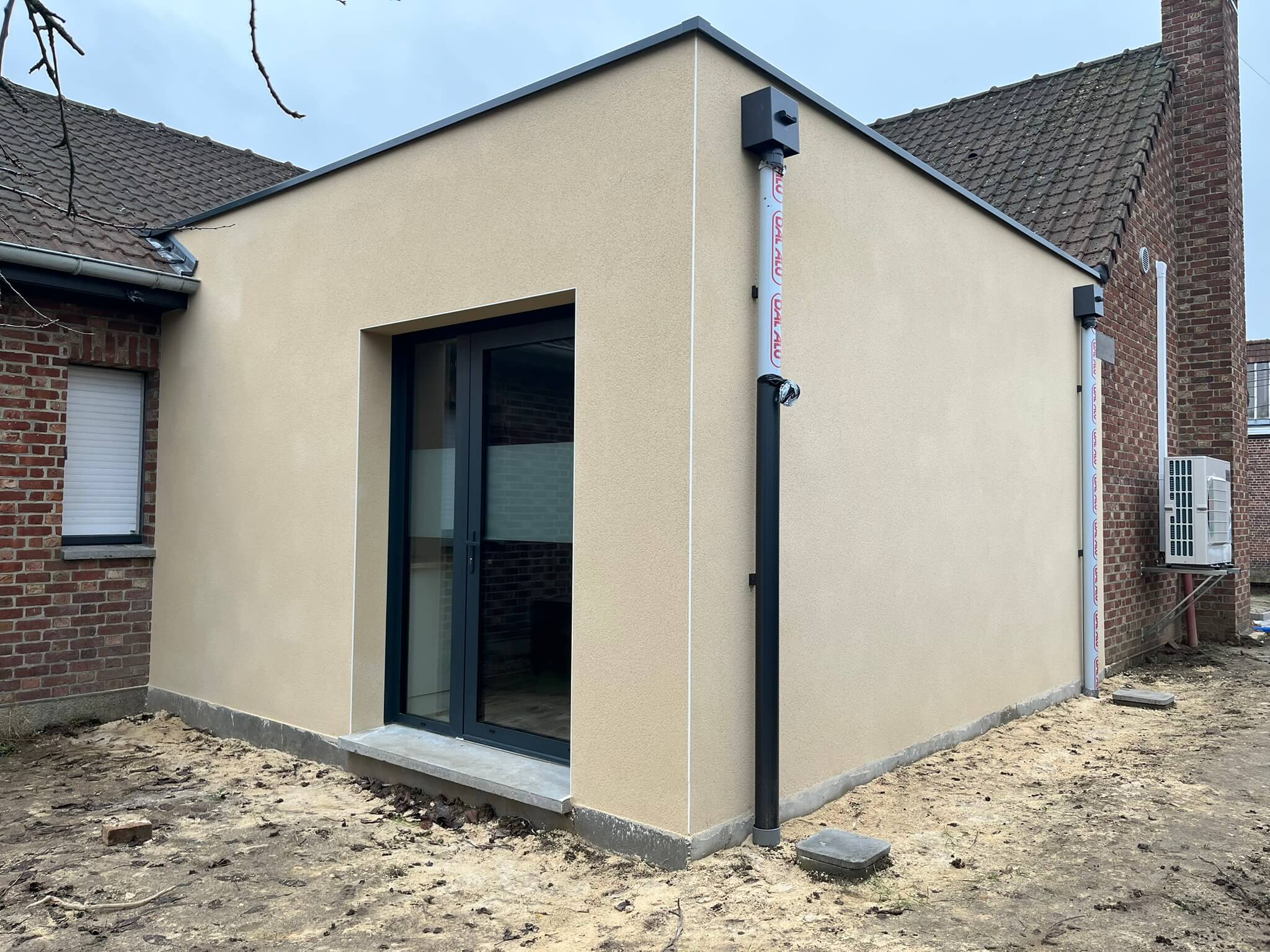 petit bâtiment beige avec une baie vitrée et un toit plat